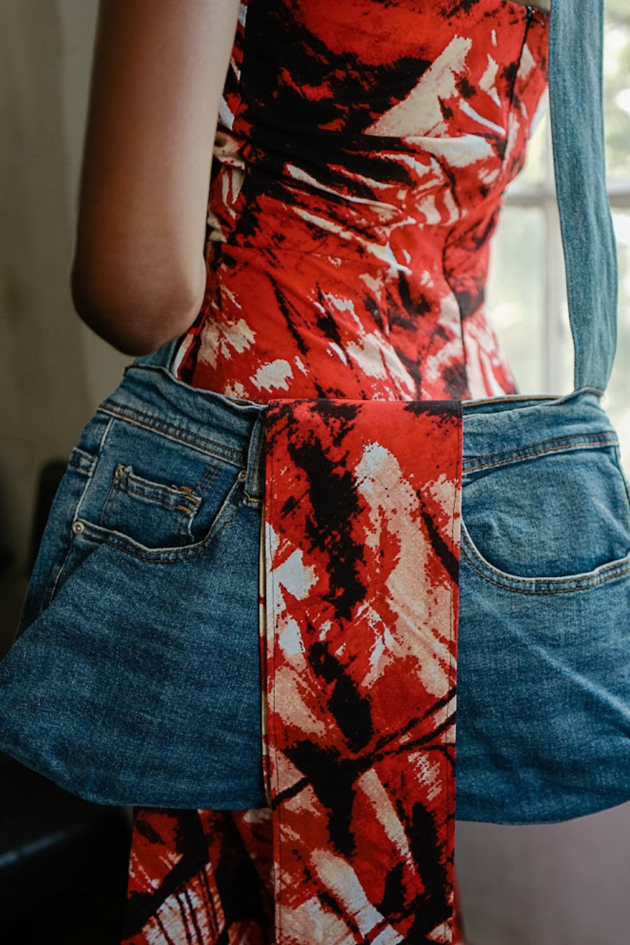 Person wearing a red and black patterned top with blue denim jacket