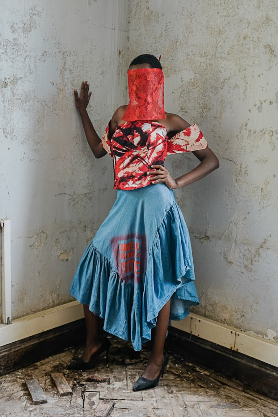 Person wearing a red and blue dress in a room with peeling paint