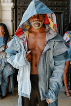 Man wearing a denim jacket with colorful inner lining, standing in front of a building entrance.